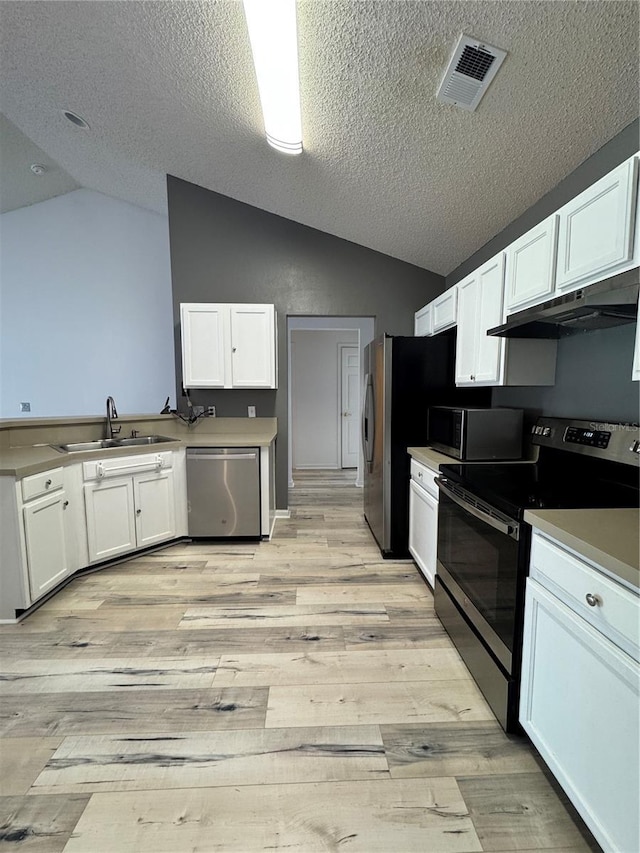 kitchen featuring a sink, under cabinet range hood, stainless steel appliances, white cabinets, and lofted ceiling