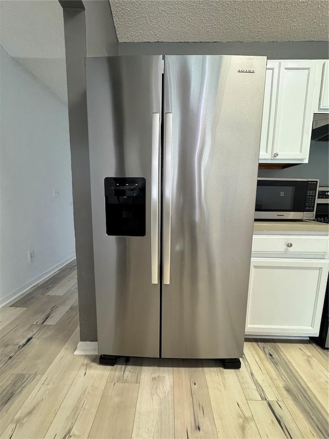 kitchen with white cabinets, appliances with stainless steel finishes, light wood-type flooring, and baseboards