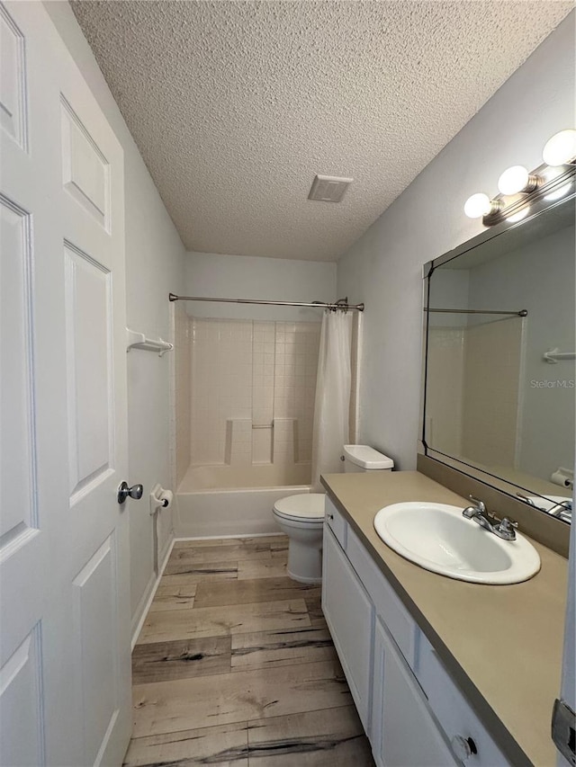 full bath with vanity, wood finished floors, visible vents, a textured ceiling, and toilet