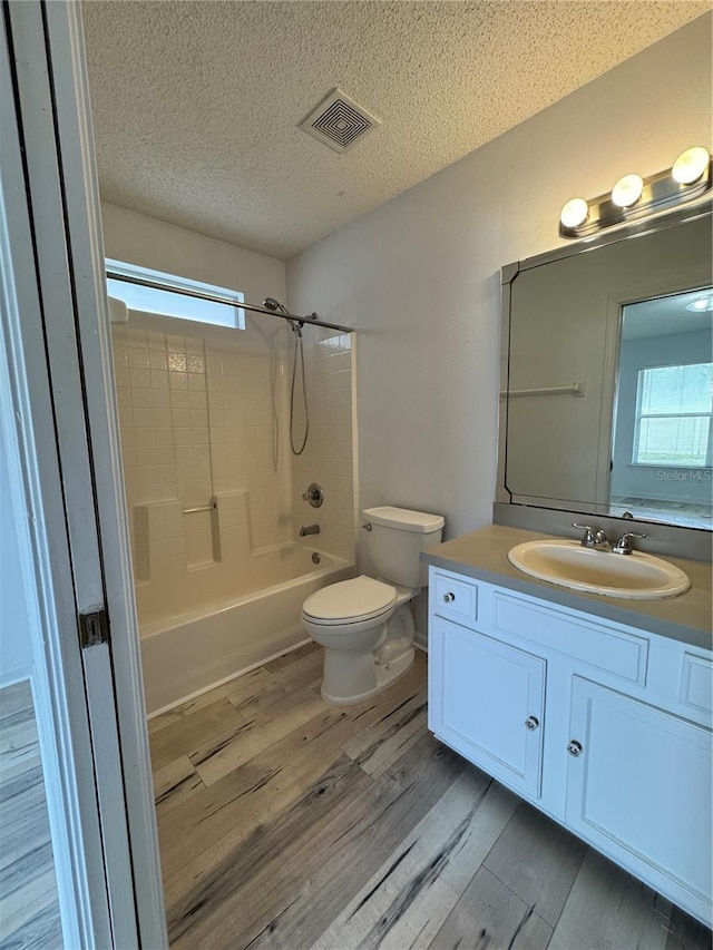 full bathroom featuring visible vents, toilet, a textured ceiling, wood finished floors, and vanity