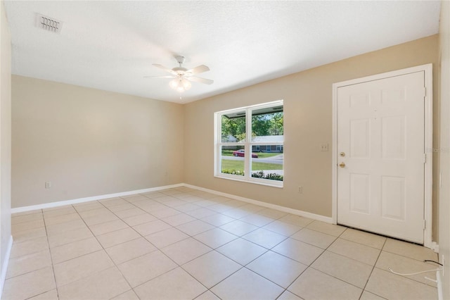 spare room featuring light tile patterned floors, visible vents, baseboards, and ceiling fan