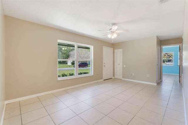 unfurnished room with light tile patterned flooring, baseboards, and ceiling fan