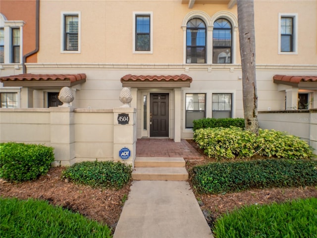 entrance to property with stucco siding and a tile roof