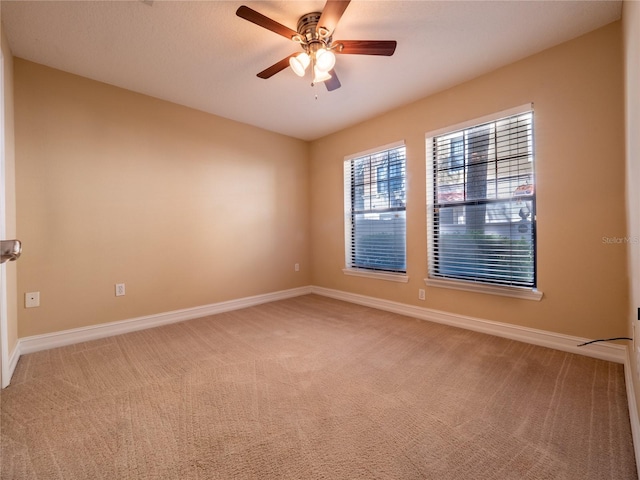 unfurnished room featuring baseboards, light colored carpet, and a ceiling fan