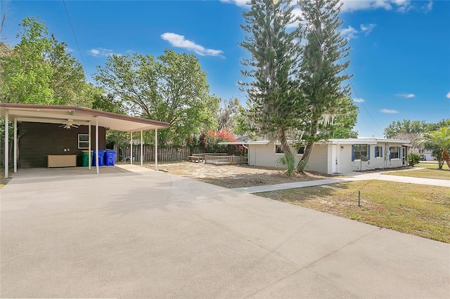 exterior space featuring a carport, driveway, a front yard, and fence