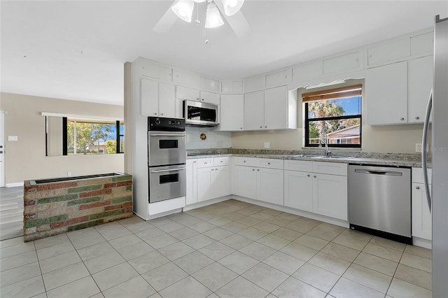 kitchen featuring white cabinetry, light stone counters, appliances with stainless steel finishes, and a sink