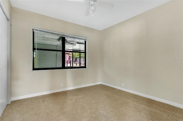 carpeted empty room with baseboards and a ceiling fan