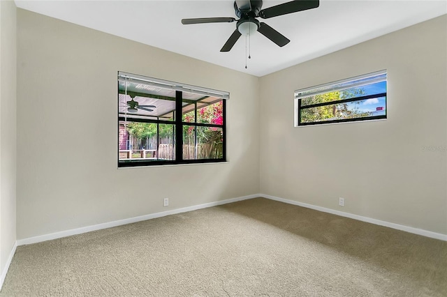 carpeted spare room with a ceiling fan and baseboards