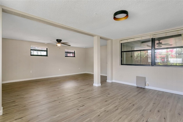 empty room with baseboards, a textured ceiling, a ceiling fan, and wood finished floors