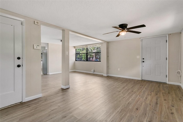 entrance foyer with a textured ceiling, light wood-type flooring, and baseboards