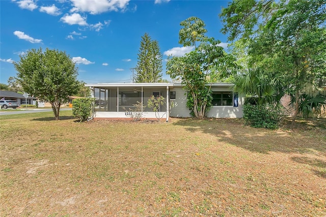 rear view of property featuring a lawn and a sunroom