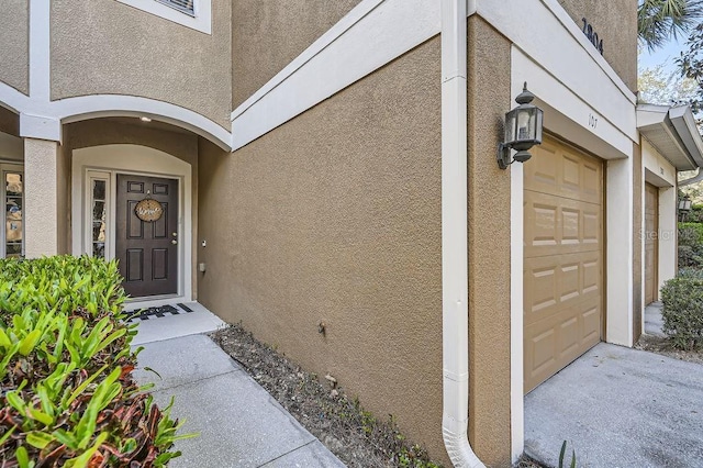 view of exterior entry featuring stucco siding and a garage