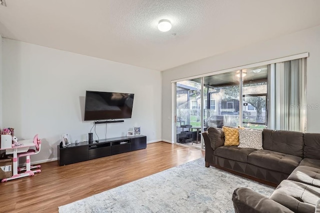 living area with baseboards, a textured ceiling, and wood finished floors