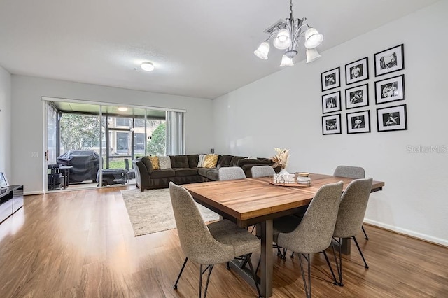 dining space with a notable chandelier, wood finished floors, and baseboards