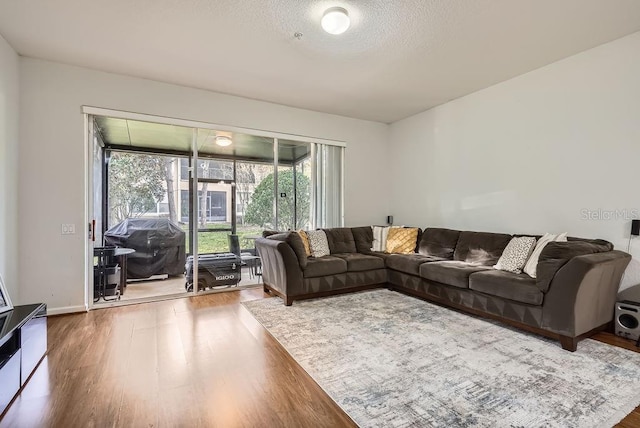 living area featuring a textured ceiling, baseboards, and wood finished floors