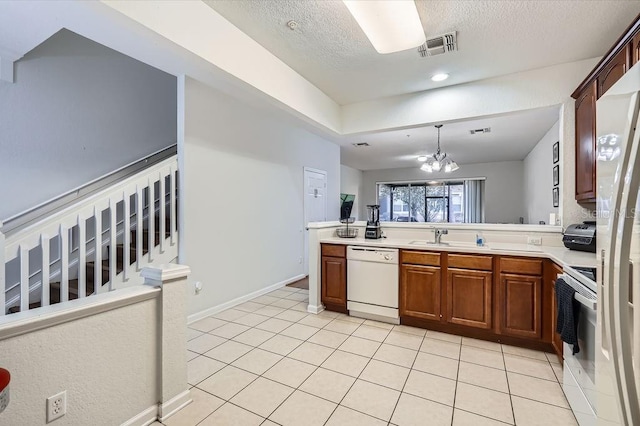 kitchen with light countertops, light tile patterned floors, white appliances, a textured ceiling, and a sink
