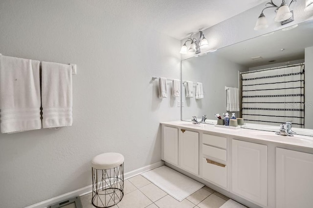 bathroom with tile patterned flooring, double vanity, baseboards, and a sink