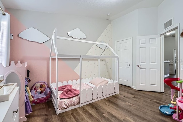 bedroom with visible vents, lofted ceiling, and wood finished floors