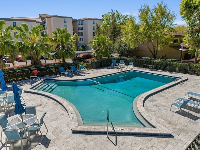 community pool with a patio area and fence