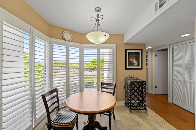 dining space with visible vents, light wood-type flooring, and baseboards