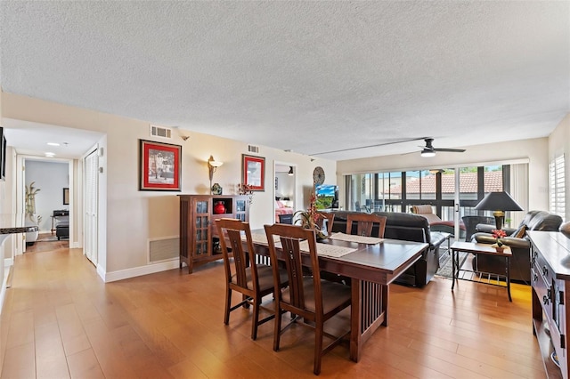 dining room featuring light wood-style flooring, visible vents, and a textured ceiling