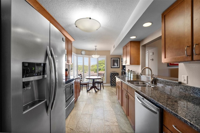 204 Quayside Cir Unit 501, Maitland, FL 32751 - kitchen with appliances with stainless steel finishes, brown cabinetry, a textured ceiling, dark stone countertops, and decorative light fixtures