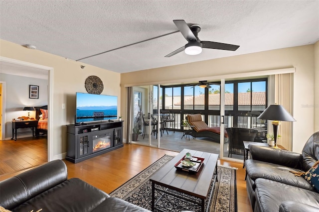 204 Quayside Cir Unit 501, Maitland, FL 32751 - living room with a textured ceiling, wood finished floors, a ceiling fan, and a glass covered fireplace