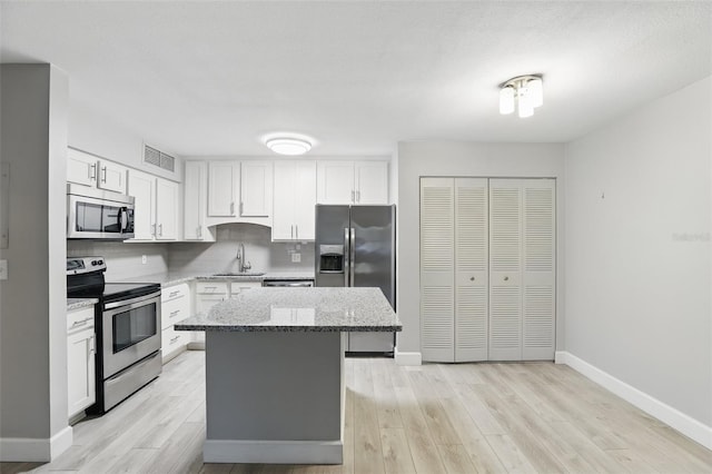 kitchen with visible vents, a center island, decorative backsplash, stainless steel appliances, and a sink