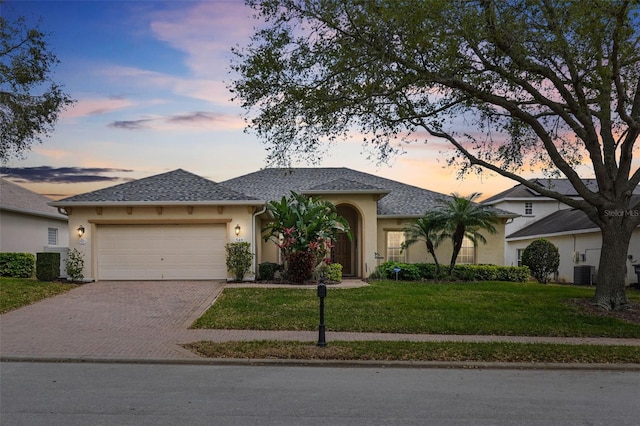 single story home featuring stucco siding, a front lawn, decorative driveway, and a garage