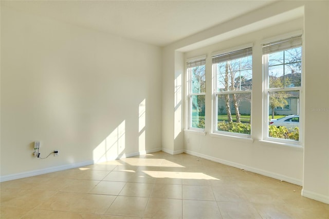 unfurnished room with a wealth of natural light, tile patterned flooring, and baseboards