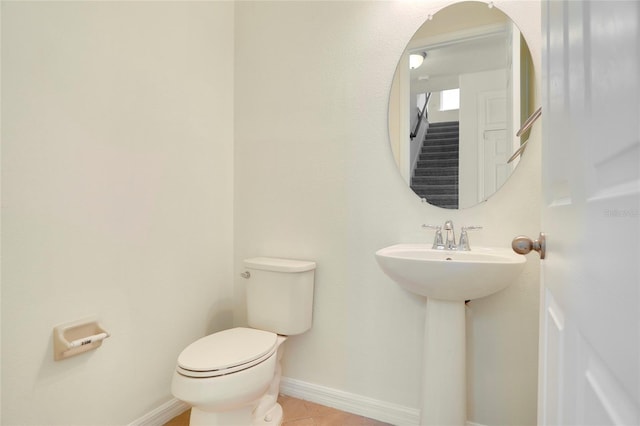 bathroom featuring tile patterned floors, toilet, baseboards, and a sink