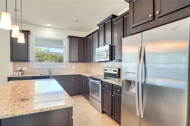 kitchen with dark brown cabinetry, light stone counters, decorative backsplash, appliances with stainless steel finishes, and a sink