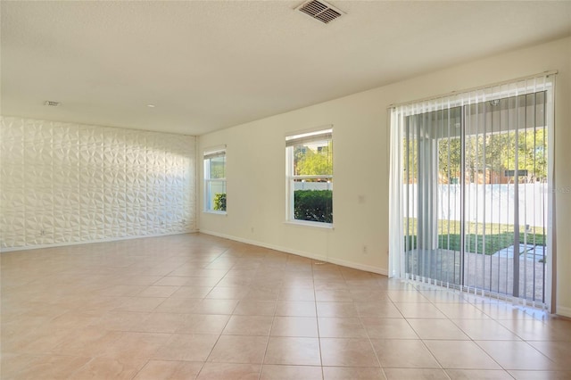 empty room featuring light tile patterned floors, visible vents, and baseboards