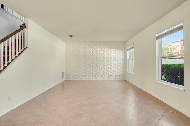 empty room featuring visible vents, baseboards, and stairs