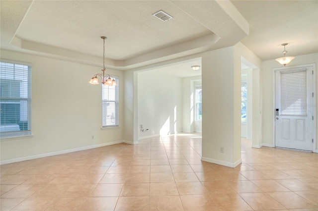 interior space with light tile patterned flooring, visible vents, baseboards, and a tray ceiling