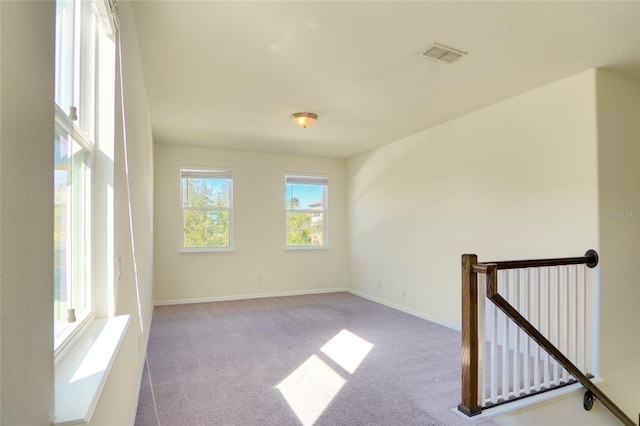 unfurnished room featuring carpet, visible vents, and baseboards