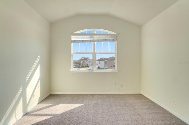 unfurnished room featuring light carpet, baseboards, and vaulted ceiling