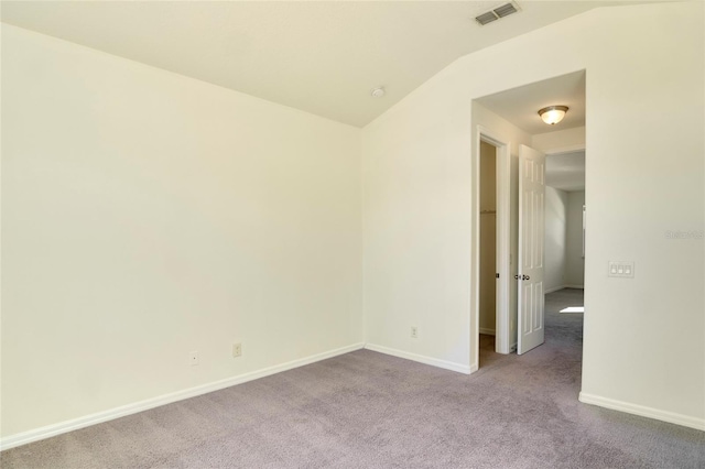 carpeted spare room with vaulted ceiling, baseboards, and visible vents