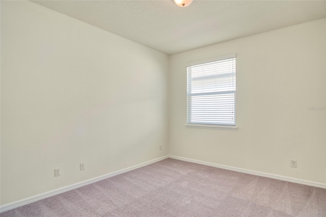 unfurnished room with baseboards, light colored carpet, and a textured ceiling