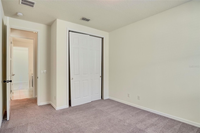 unfurnished bedroom with visible vents, baseboards, a closet, and carpet flooring