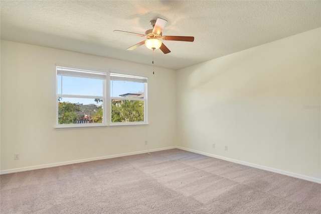 spare room with a textured ceiling, a ceiling fan, baseboards, and light carpet