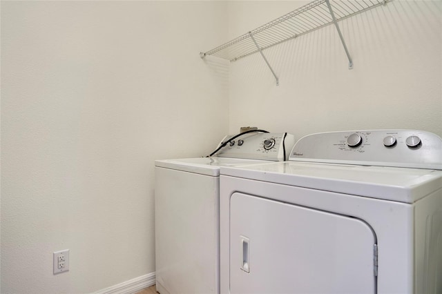 clothes washing area featuring baseboards, laundry area, and washing machine and clothes dryer