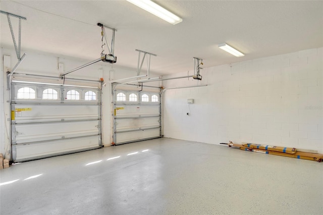 garage featuring a garage door opener and concrete block wall