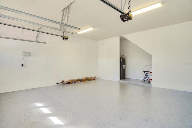 garage featuring concrete block wall, a garage door opener, and water heater