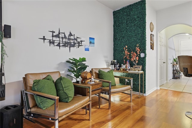 sitting room featuring wood finished floors, arched walkways, and baseboards