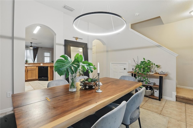 dining space featuring light tile patterned floors, visible vents, arched walkways, and a ceiling fan