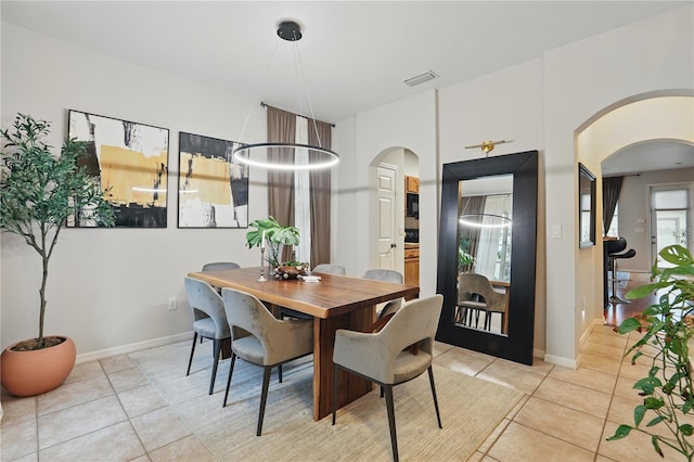 dining area featuring light tile patterned floors, visible vents, arched walkways, and baseboards