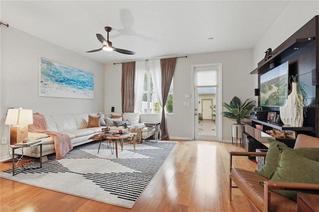 living room with a ceiling fan, wood finished floors, and baseboards