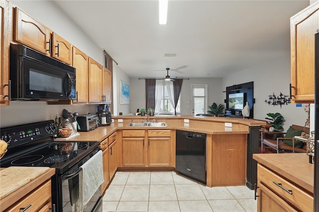 kitchen featuring light tile patterned floors, a peninsula, a sink, black appliances, and light countertops