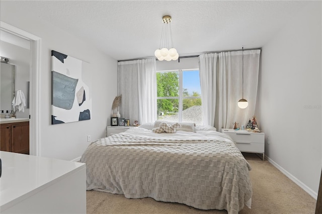 bedroom with a textured ceiling, a sink, baseboards, and light carpet